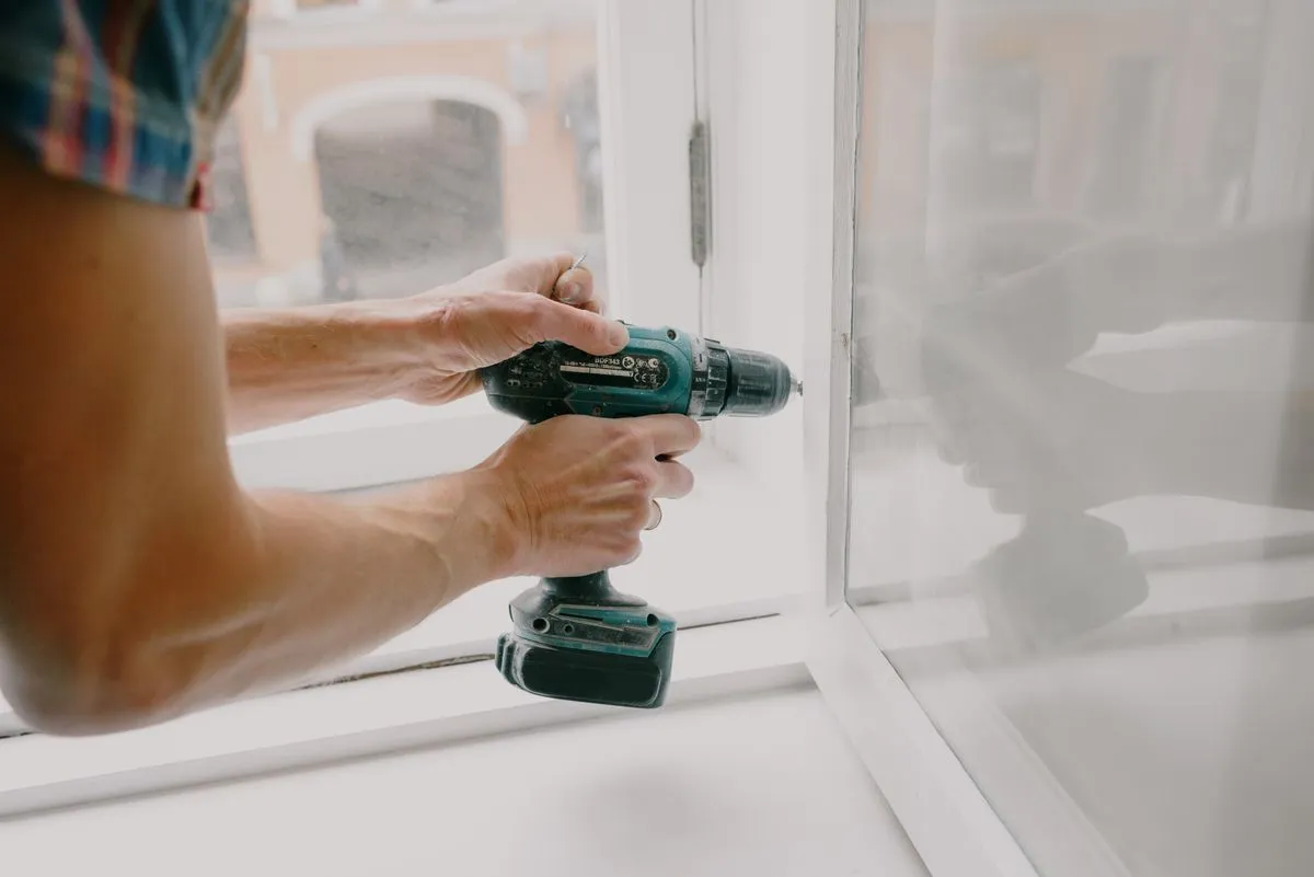 Technician repairing a window with a screwdriver during a service call